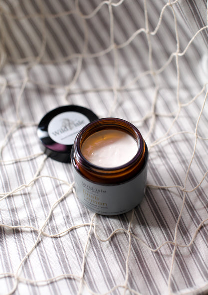 Jar of cream on a textured surface with wild isle skincare