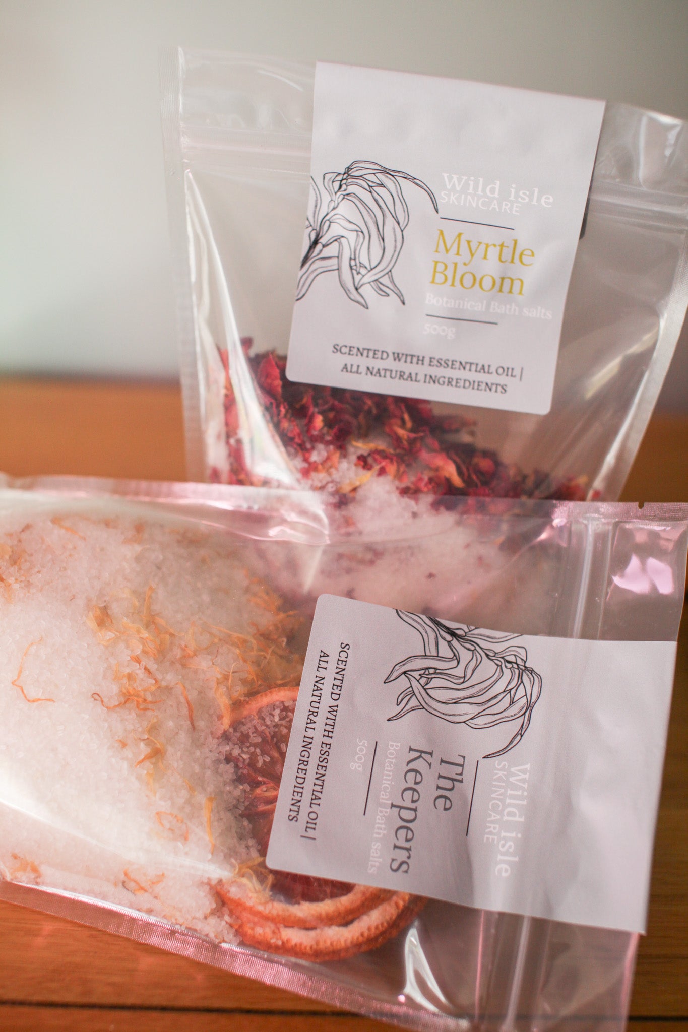 Two packages of 'Myrtle Bloom' by 'The Keepers' on a wooden surface.