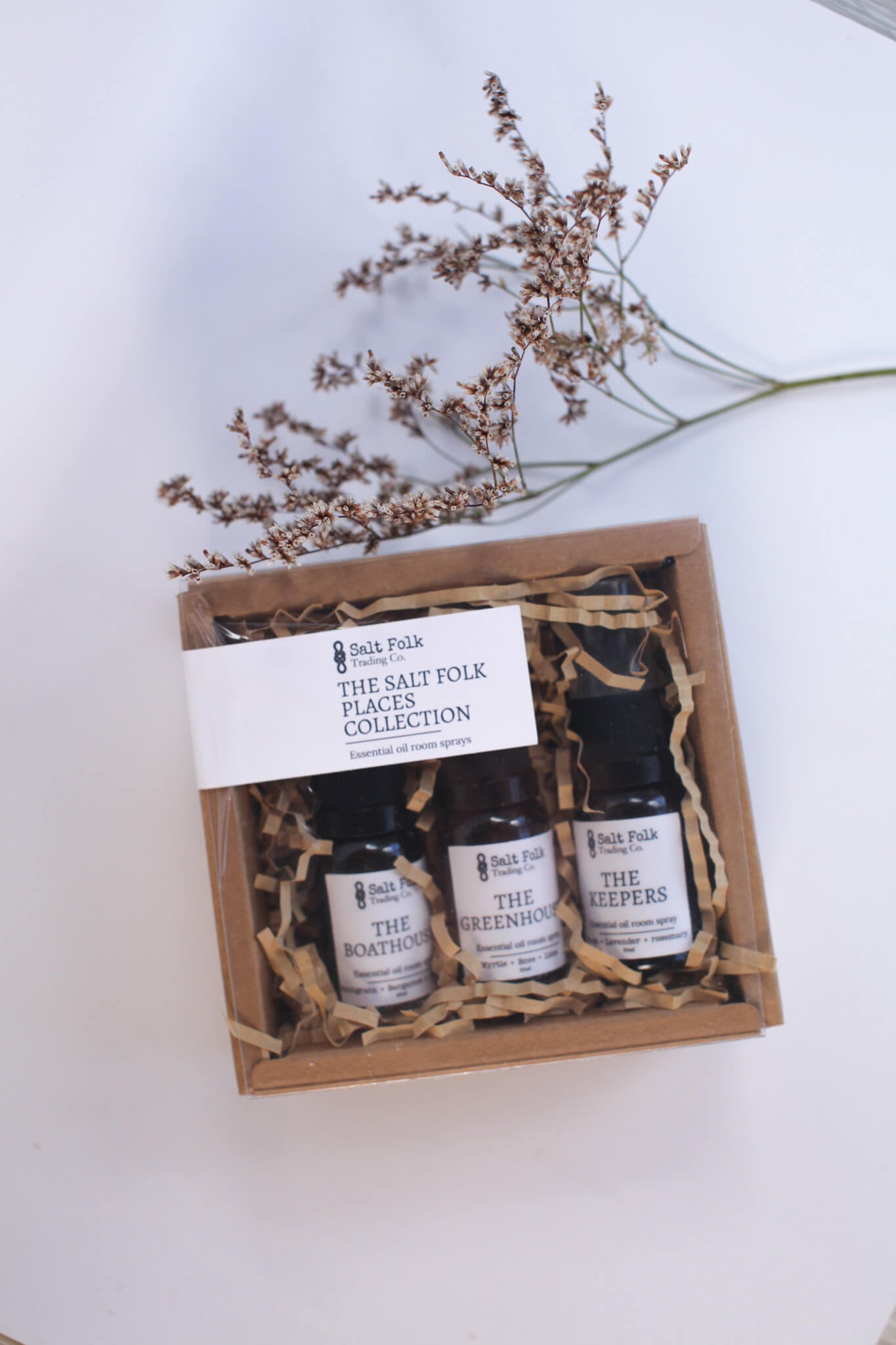 Set of three small bottles in a wooden gift box with decorative paper, on a light background.