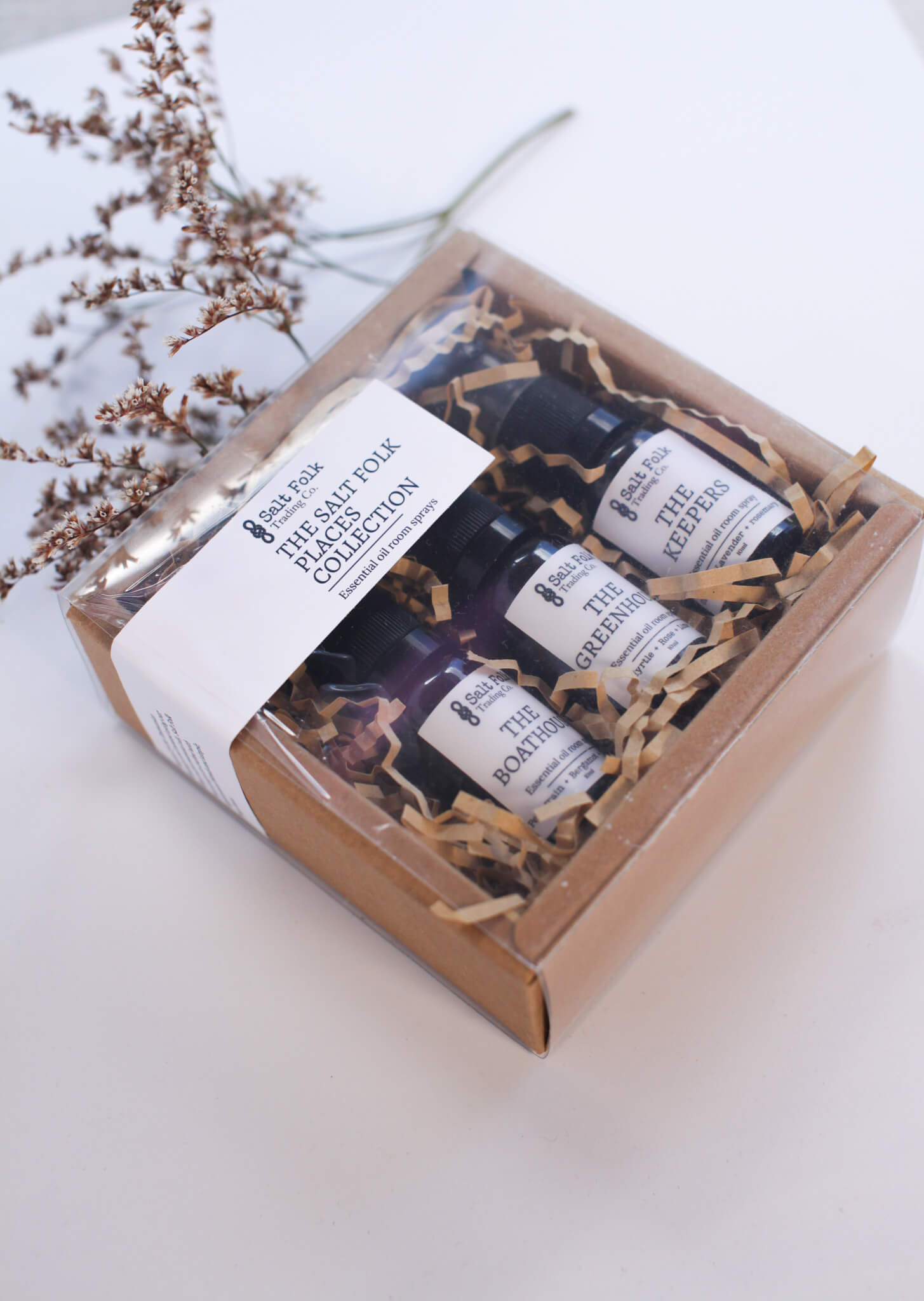 Set of small bottles in a decorative box with brown paper lining on a white surface.